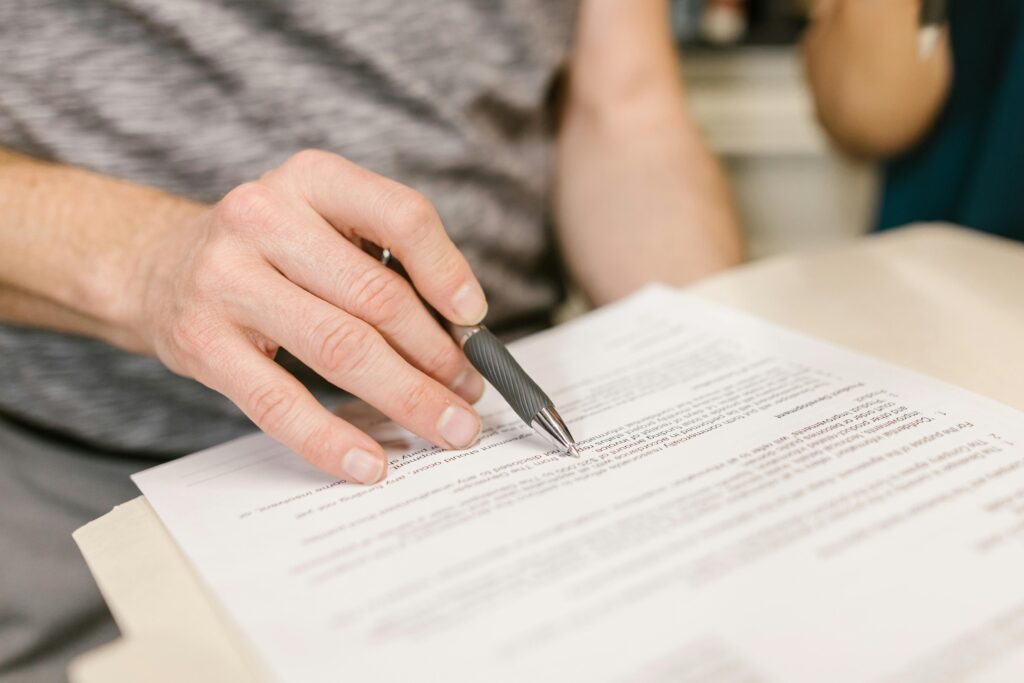 A hand holding a pen over a printed document on a desk.